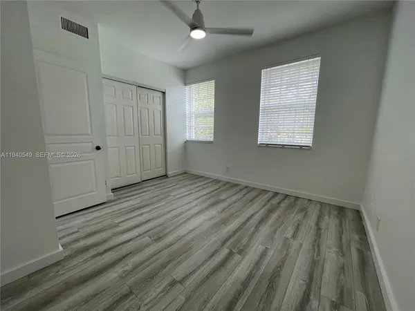 an empty room with wooden floor and windows