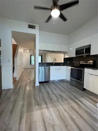 a view of a kitchen with a sink a kitchen counter space stainless steel appliances and cabinets