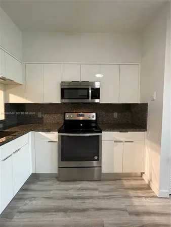 a kitchen with granite countertop a stove and a microwave