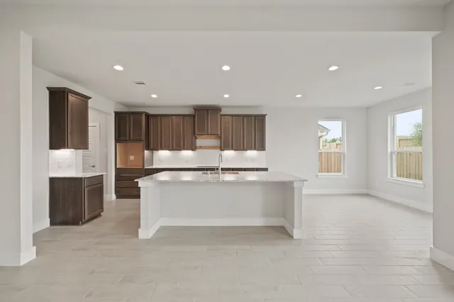 a large white kitchen with kitchen island a sink stainless steel appliances and cabinets