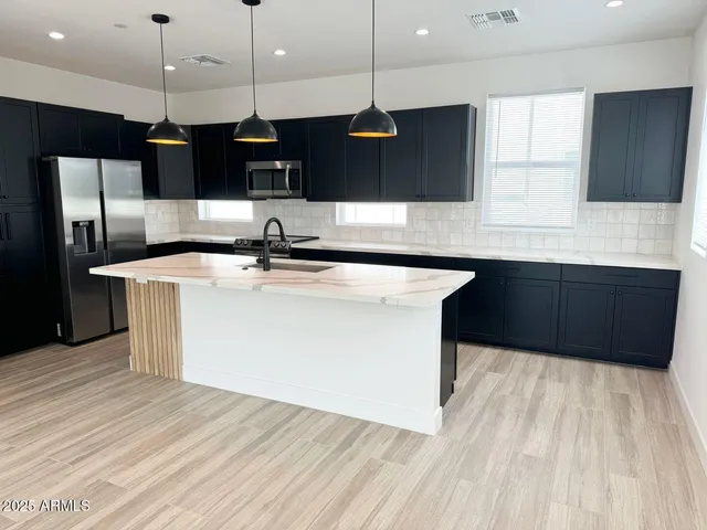 a kitchen with stainless steel appliances a sink a microwave a refrigerator and cabinets