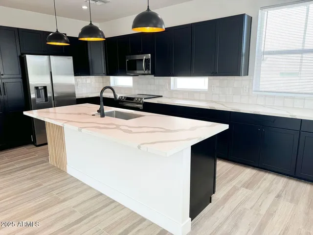 a kitchen with stainless steel appliances granite countertop a sink a stove and a refrigerator