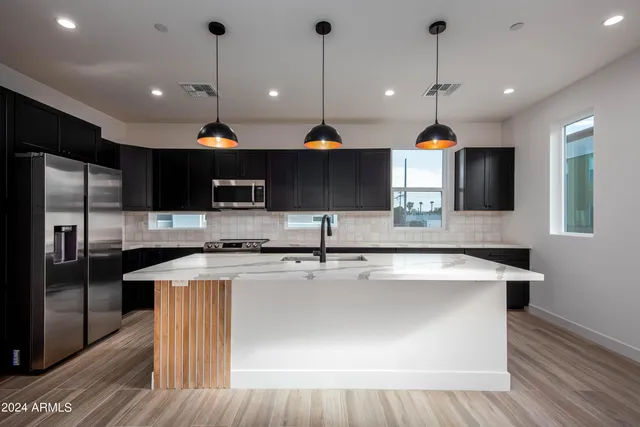 a kitchen with stainless steel appliances granite countertop sink a stove and a refrigerator