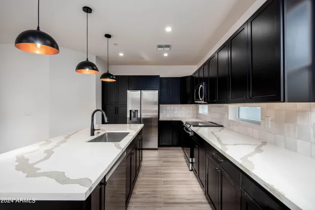 a kitchen with kitchen island granite countertop a sink a counter space appliances and a window