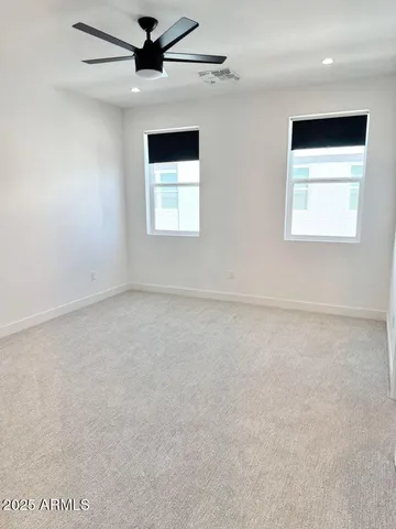 an empty room with a ceiling fan and carpet