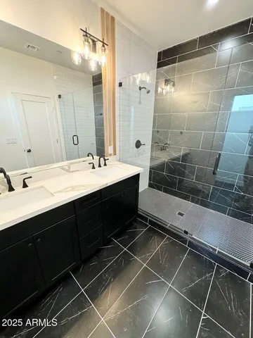 a bathroom with a double vanity sink mirror and shower
