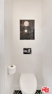 a bathroom with a toilet and a picture on the wall