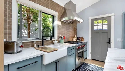 a kitchen that has a lot of cabinets a stove and a wooden floor