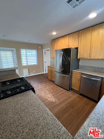 a kitchen with granite countertop a refrigerator and a stove top oven