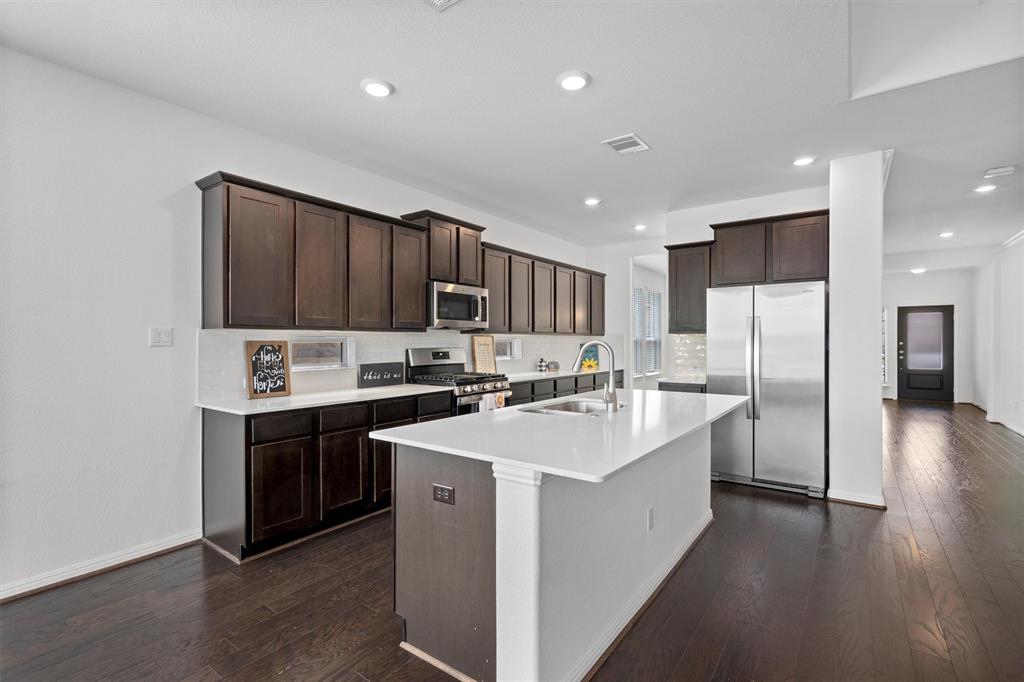 236 Prato Place Georgetown, TX 78628 - Photo 13 of 40 Bright, open-concept kitchen with sleek, dark cabinetry, pristine white countertops, and gleaming hardwood floors.