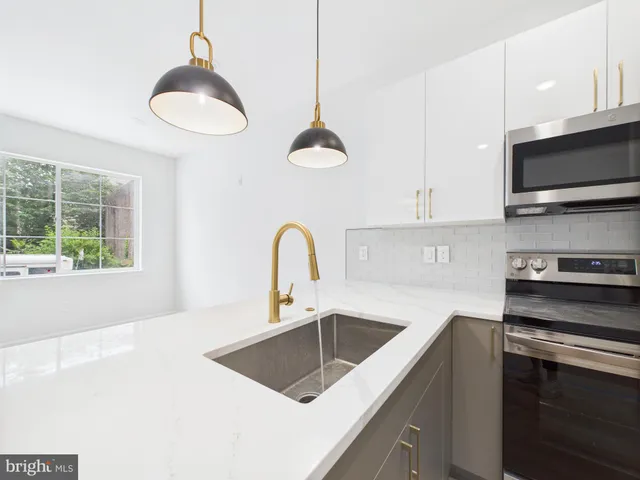 a kitchen with stainless steel appliances granite countertop a sink a stove and a microwave