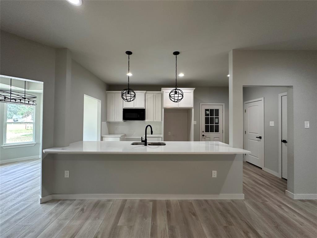 317 North Clark Street Comanche, TX 76442 - Photo 12 of 35 a large kitchen with stainless steel appliances a large counter top and a wooden floors
