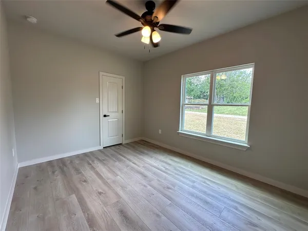 an empty room with wooden floor and a ceiling fan