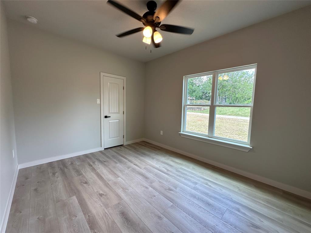 317 North Clark Street Comanche, TX 76442 - Photo 14 of 35 a view of an empty room with window and wooden floor