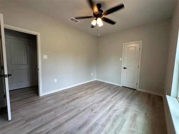 an empty room with window and ceiling fan