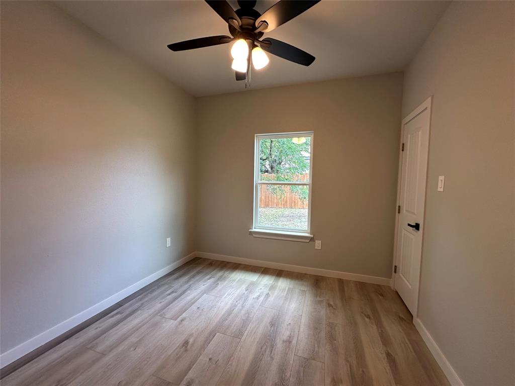317 North Clark Street Comanche, TX 76442 - Photo 17 of 35 an empty room with a window and wooden floor