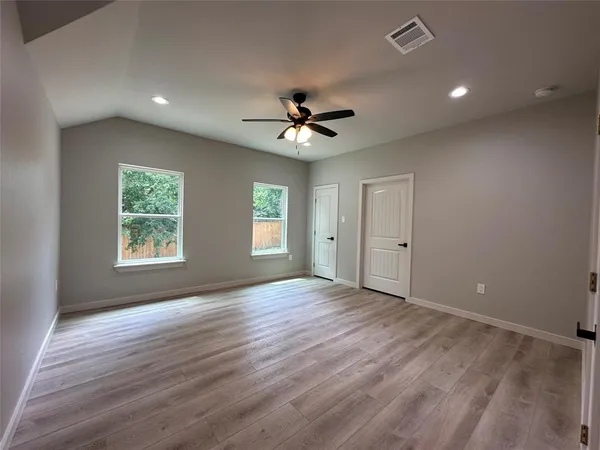 a view of an empty room with a window and wooden floor