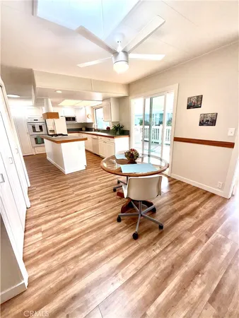 a view of a kitchen with kitchen island stainless steel appliances wooden floor and view living room