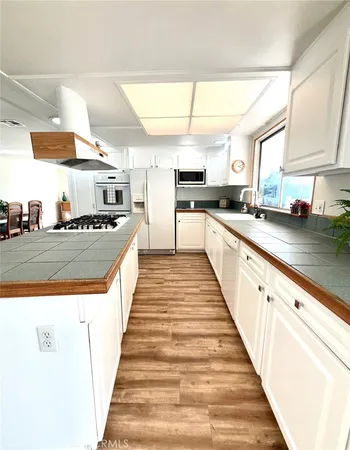 a large white kitchen with stainless steel appliances a sink and counter