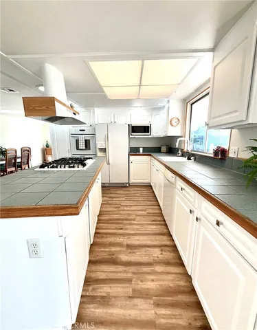 a large white kitchen with stainless steel appliances a sink and counter