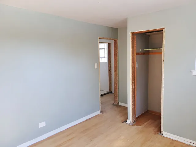 a view of an empty room with closet and a window