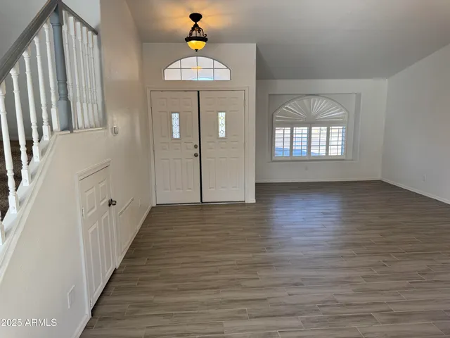 a kitchen with stainless steel appliances a refrigerator a sink dishwasher a stove top oven a dining table and chairs with wooden floor