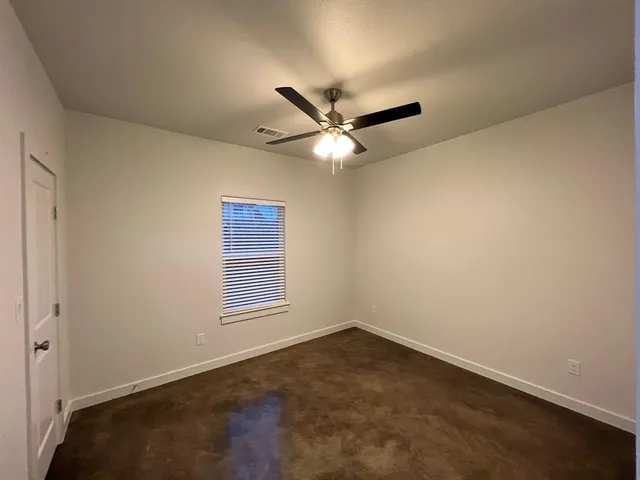 an empty room with a window and a ceiling fan