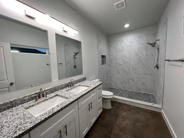 a bathroom with a granite countertop sink a toilet and shower