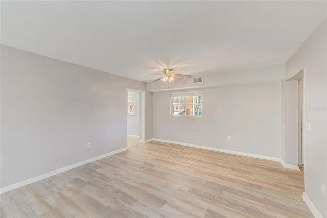 a view of an empty room with a window and wooden floor