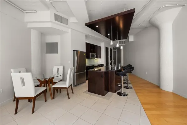 a kitchen with stainless steel appliances kitchen island granite countertop a table chairs and a refrigerator