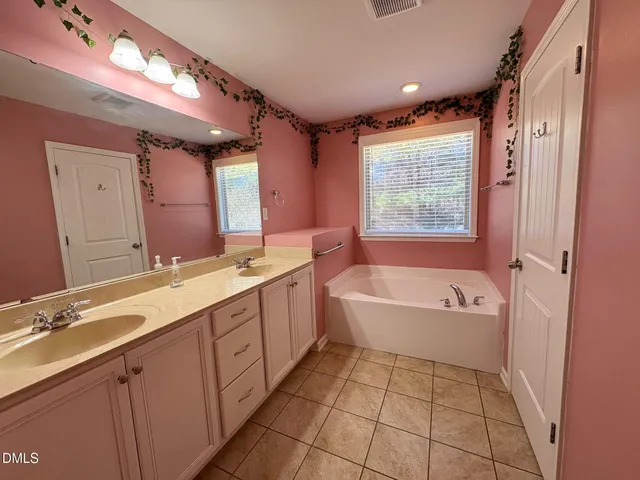 a spacious bathroom with a double vanity sink a mirror and a bathtub