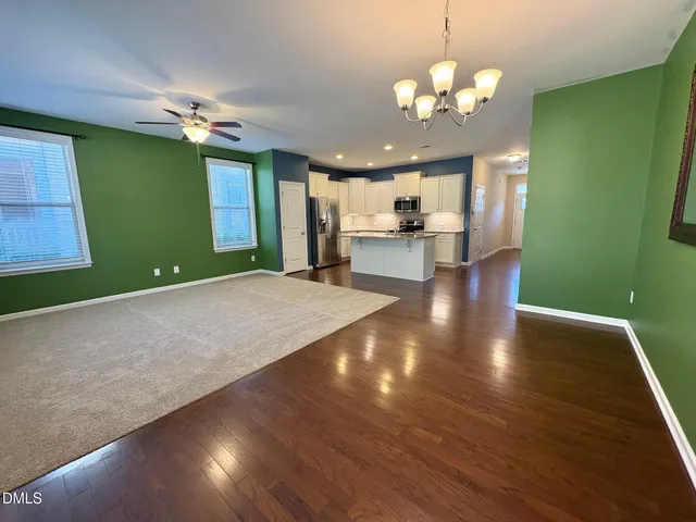 a view of a livingroom with a chandelier fan and kitchen view