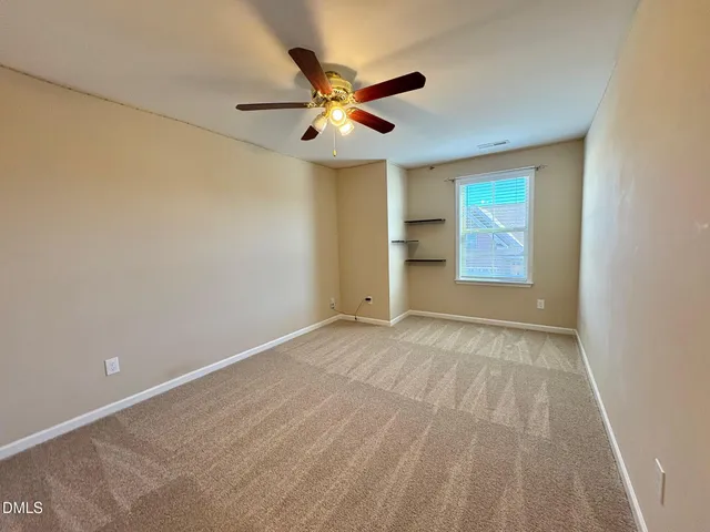 an empty room with closet and ceiling fan