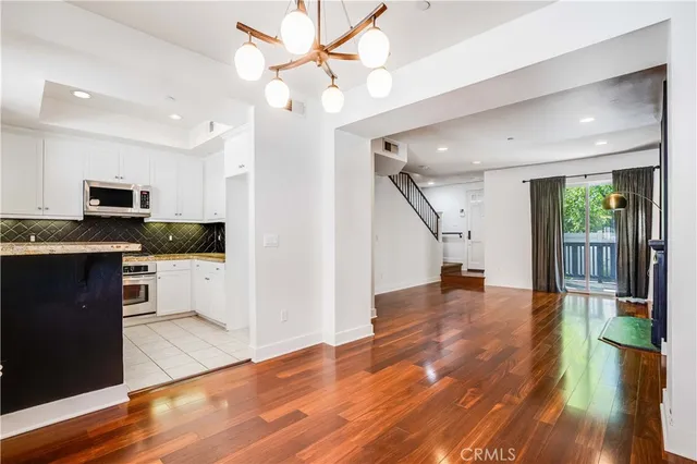 a view of a kitchen with wooden floor and a kitchen space with a sink