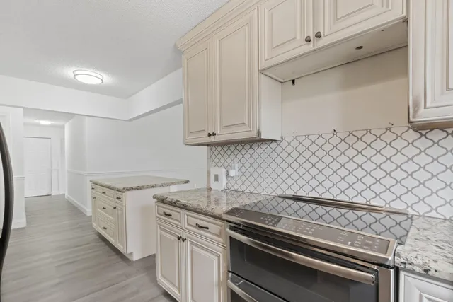 a kitchen with granite countertop white cabinets and stainless steel appliances