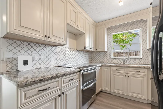 a kitchen with granite countertop white cabinets white appliances and sink
