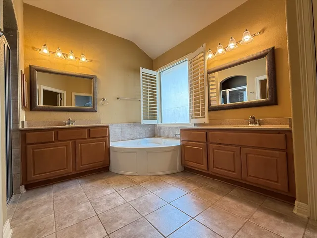 a bathroom with a granite countertop double vanity sink a mirror and a bathtub