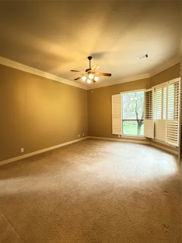 an empty room with chandelier fan and windows