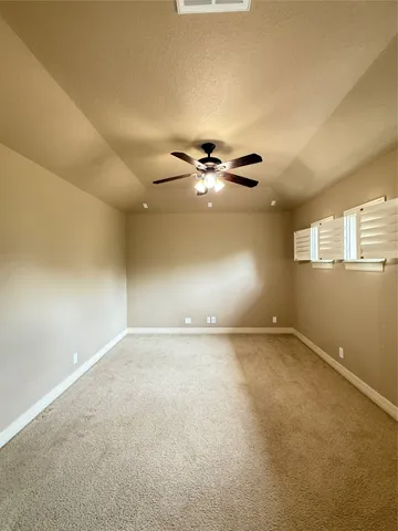 an empty room with a ceiling fan and window