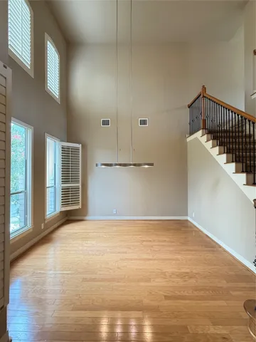a view of an empty room with wooden floor and windows