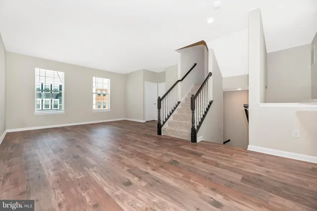 a view of an empty room with wooden floor and stairs