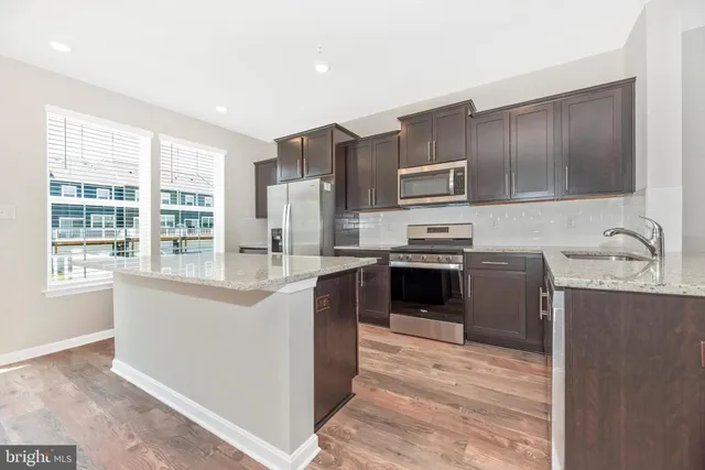 a large kitchen with stainless steel appliances granite countertop a stove a sink a refrigerator and a sink