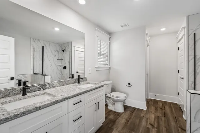 a bathroom with a granite countertop sink a toilet and a large mirror