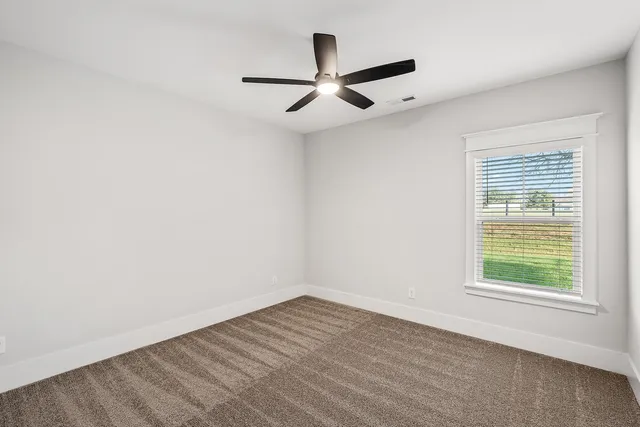 an empty room with wooden floor ceiling fan and windows