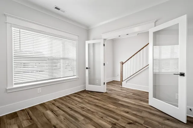 a view of an empty room with wooden floor and a window