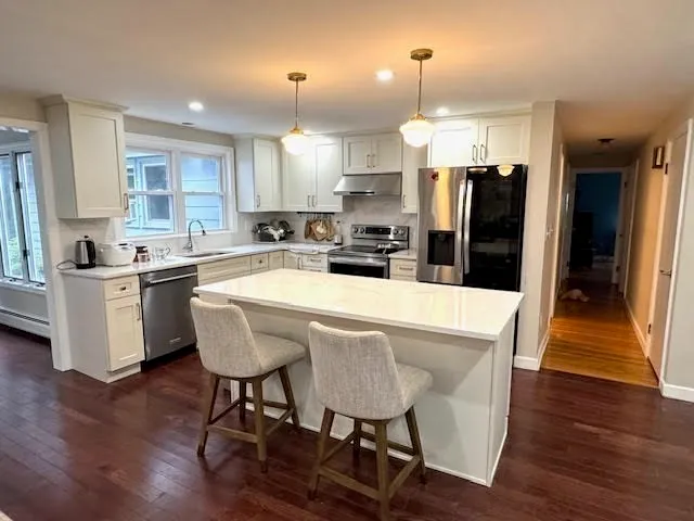 a kitchen with stainless steel appliances a dining table chairs refrigerator and sink