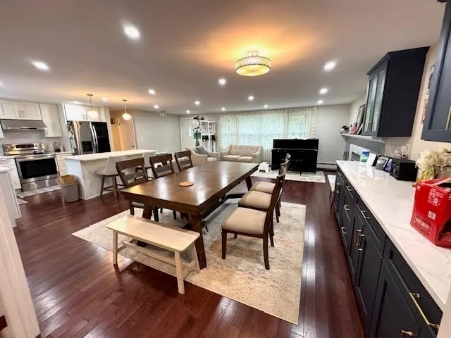 a living room with stainless steel appliances furniture a rug and a kitchen view
