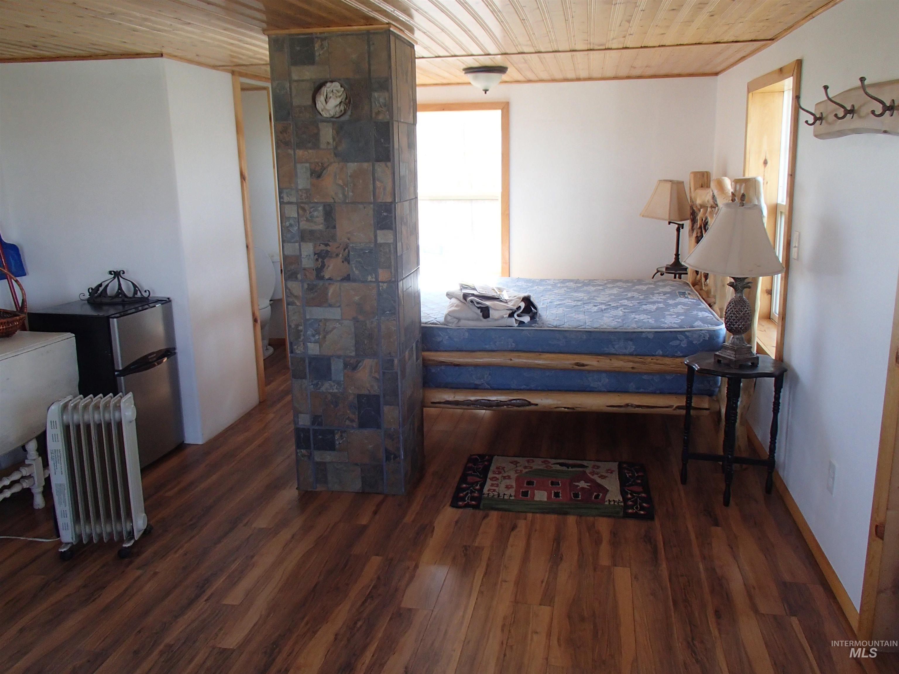 9506 Wright Road Melba, ID 83641 - Photo 19 of 37 Bedroom featuring wood ceiling, radiator heating unit, dark wood-type flooring, and freestanding refrigerator