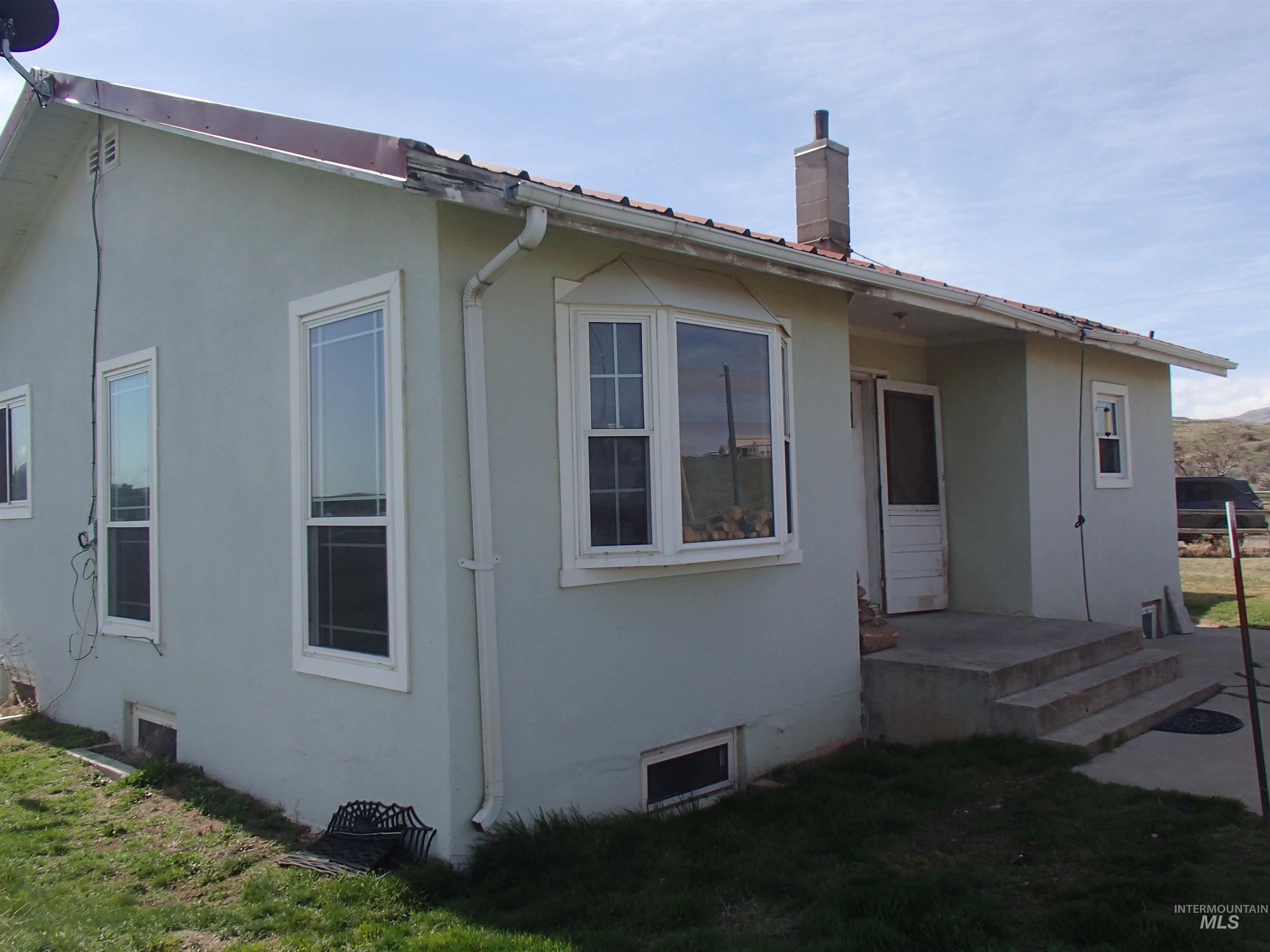 9506 Wright Road Melba, ID 83641 - Photo 2 of 37 view of house featuring stucco siding, a chimney, and a yard