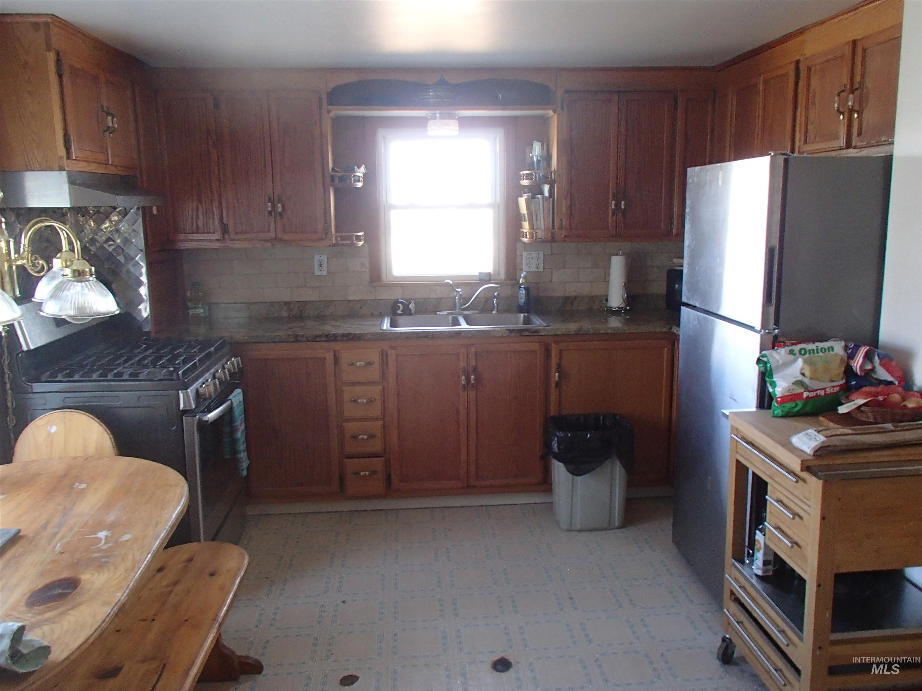 9506 Wright Road Melba, ID 83641 - Photo 5 of 37 Kitchen with light floors, wood finish cabinets, stainless steel appliances, and decorative backsplash